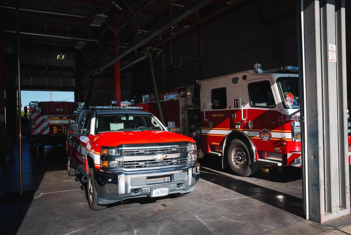Fire station garage with red and white Chevrolet truck from Colorado at the forefront, ready for deployment. Sparks Fire Rescue fire engine parked in the background. Urban setting. photo