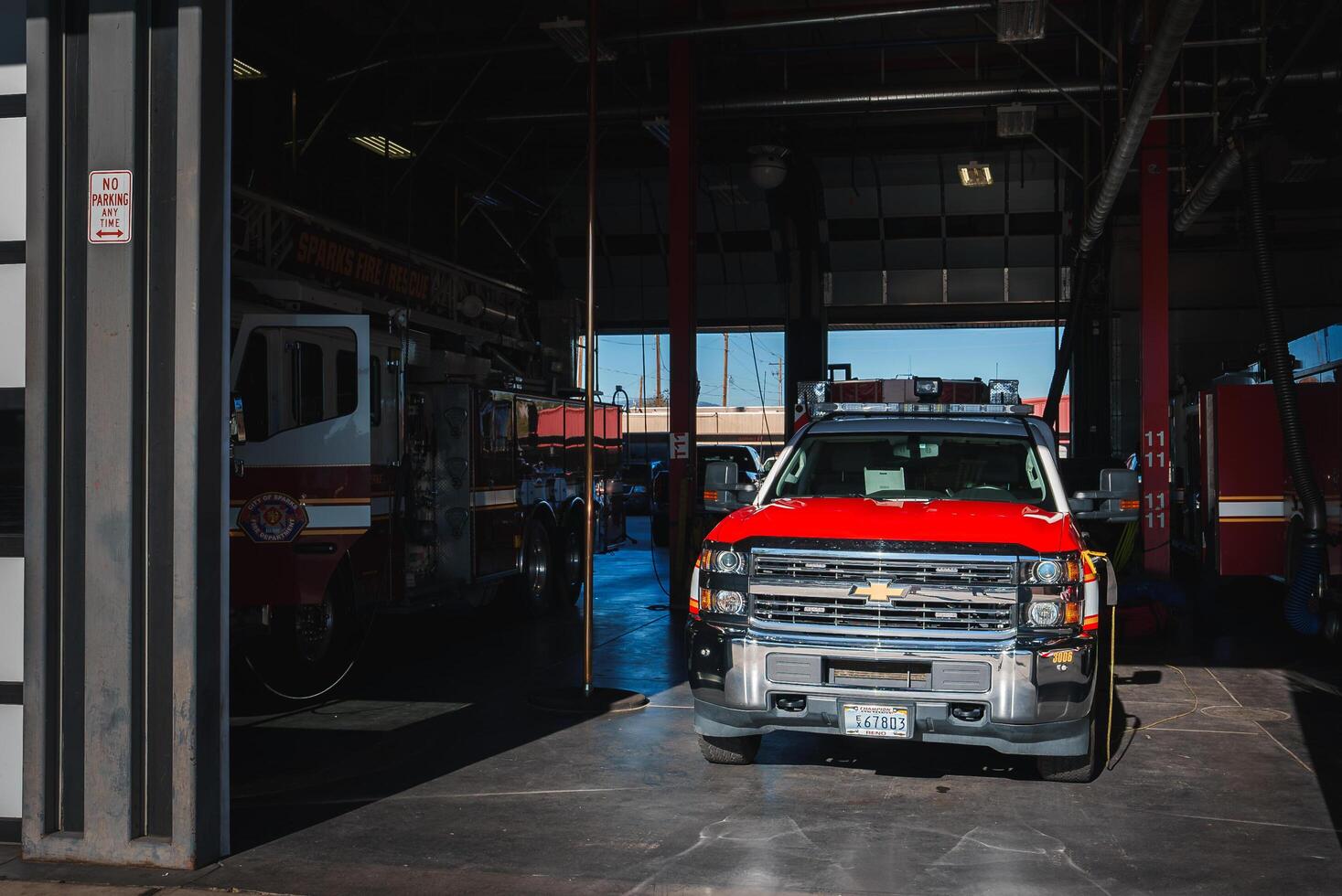 Fire station garage with red and white Chevrolet truck from Colorado at the forefront, ready for deployment. Sparks Fire Rescue fire engine parked in the background. Urban setting. photo