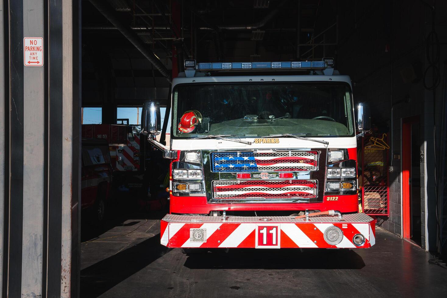 Fire station garage with red and white Chevrolet truck from Colorado at the forefront, ready for deployment. Sparks Fire Rescue fire engine parked in the background. Urban setting. photo