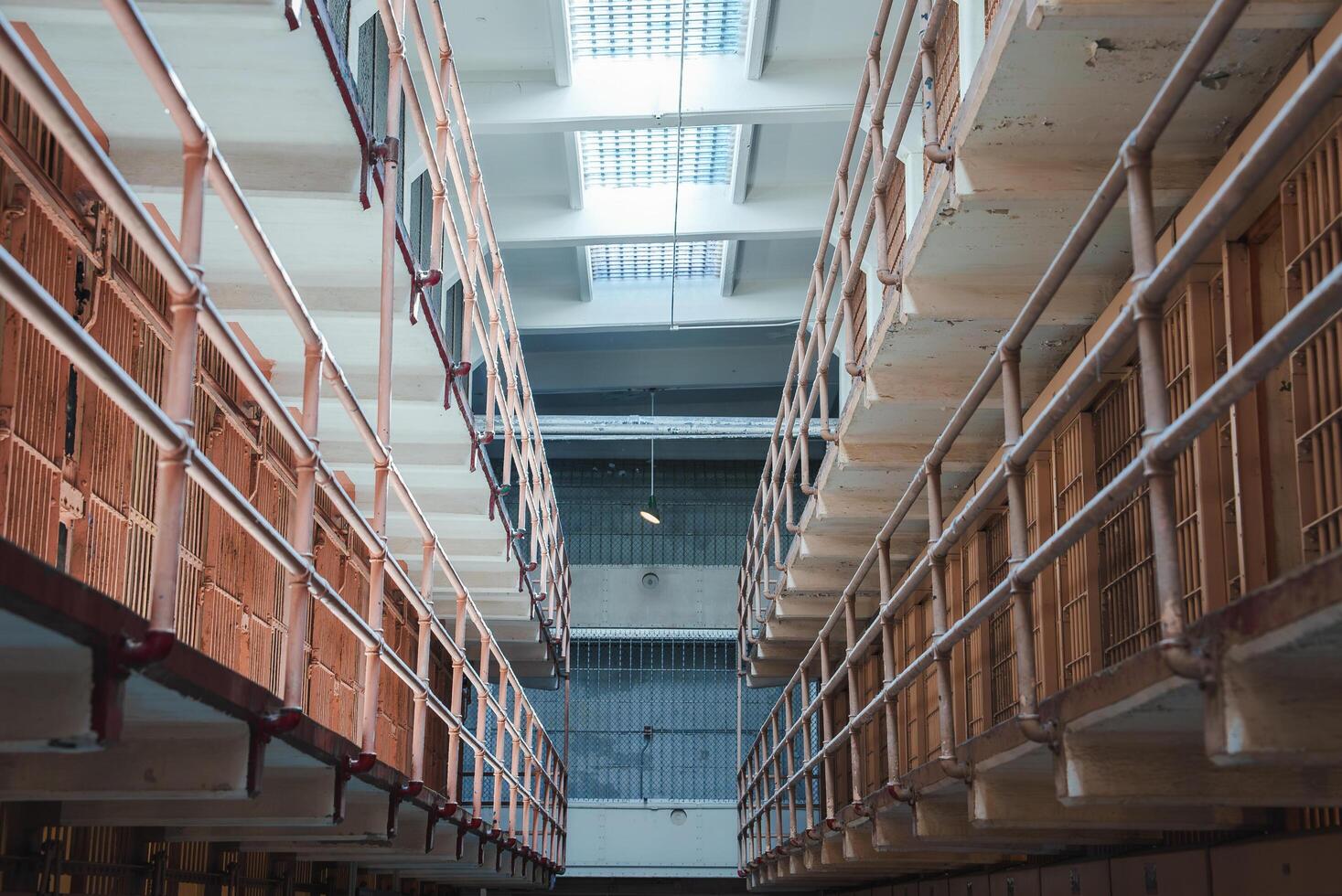 Interior view of Alcatraz prison in San Francisco, USA. Cell block corridor lined with small cells, rusted bars, peeling paint. Stark atmosphere, historical significance. photo