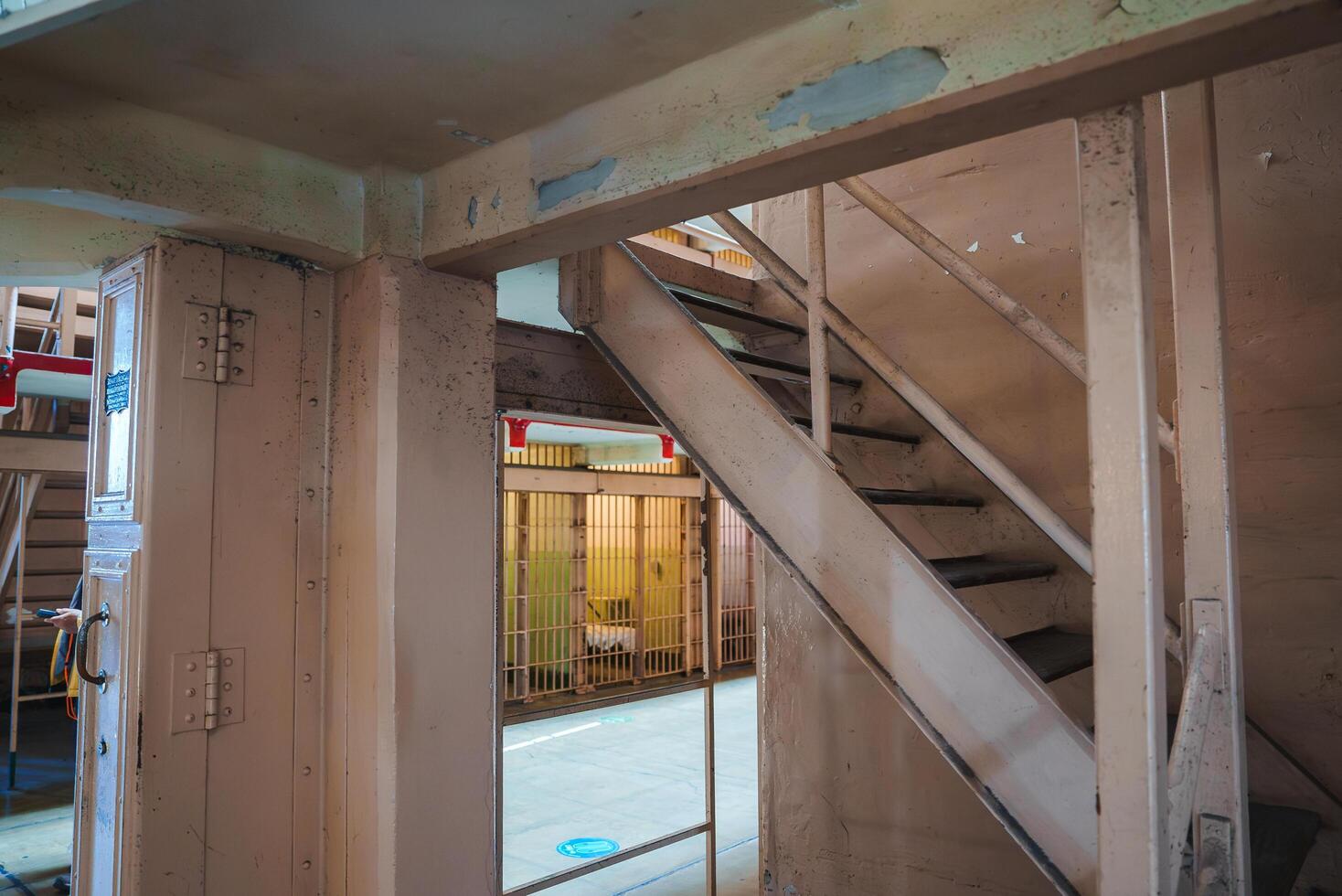 Interior view of Alcatraz prison in San Francisco, USA. Concrete walls, peeling paint, warm artificial lighting, barred gate, atmosphere of historical decay and abandonment. photo