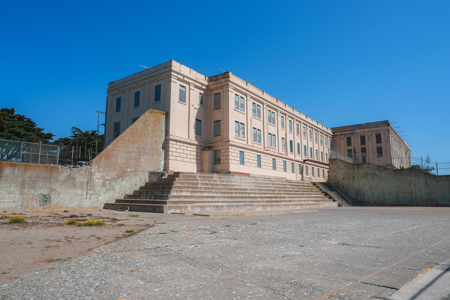 View the iconic Alcatraz prison in San Francisco, USA, showcasing a grand beige building with multiple windows, a central entrance, and two sets of stairs. photo