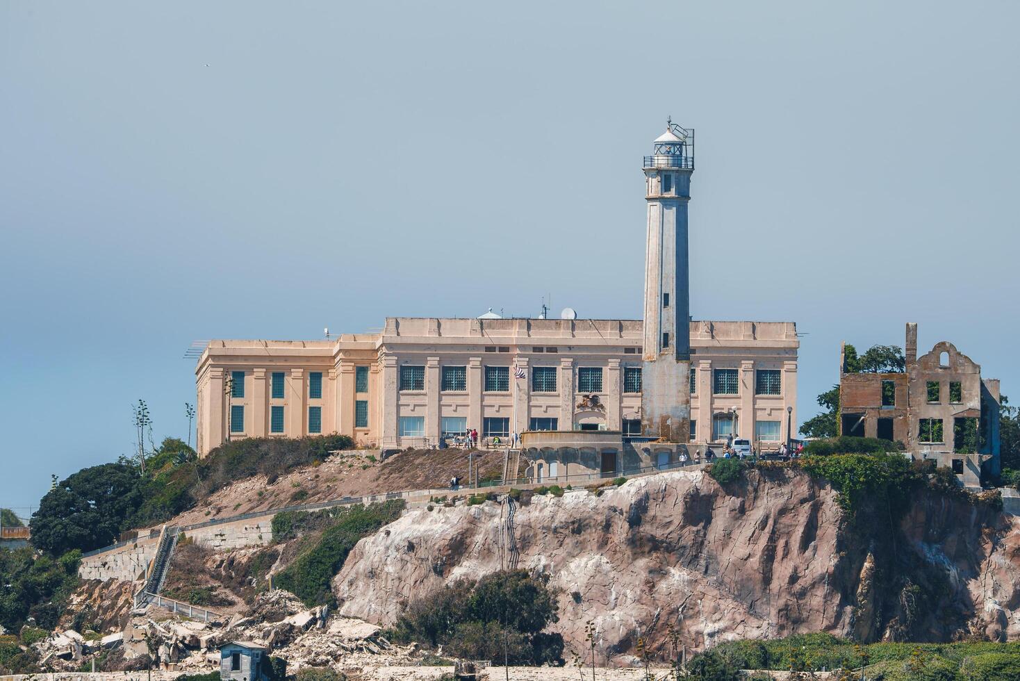 View of Alcatraz Federal Penitentiary on Alcatraz Island in San Francisco Bay, California, USA. Shows prison, lighthouse, and historical ruins against blue sky. photo