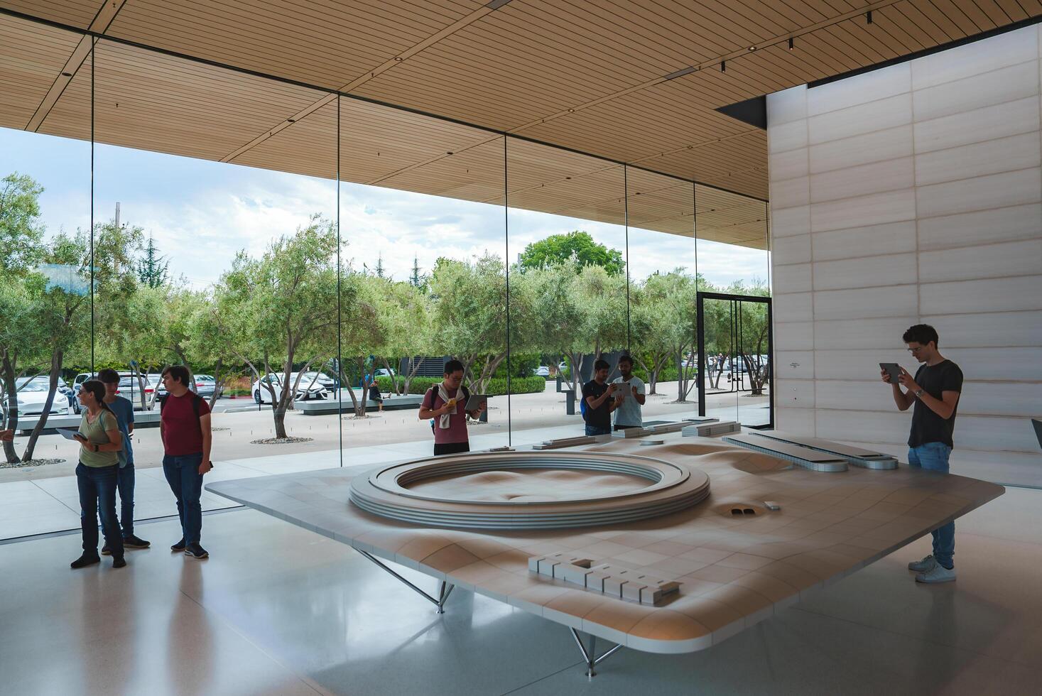 Interior of Apple Store in Mountain View, CA. Modern, minimalist design with large windows, wooden panels, and a warm ambiance. Customers browsing products and staff assisting. photo