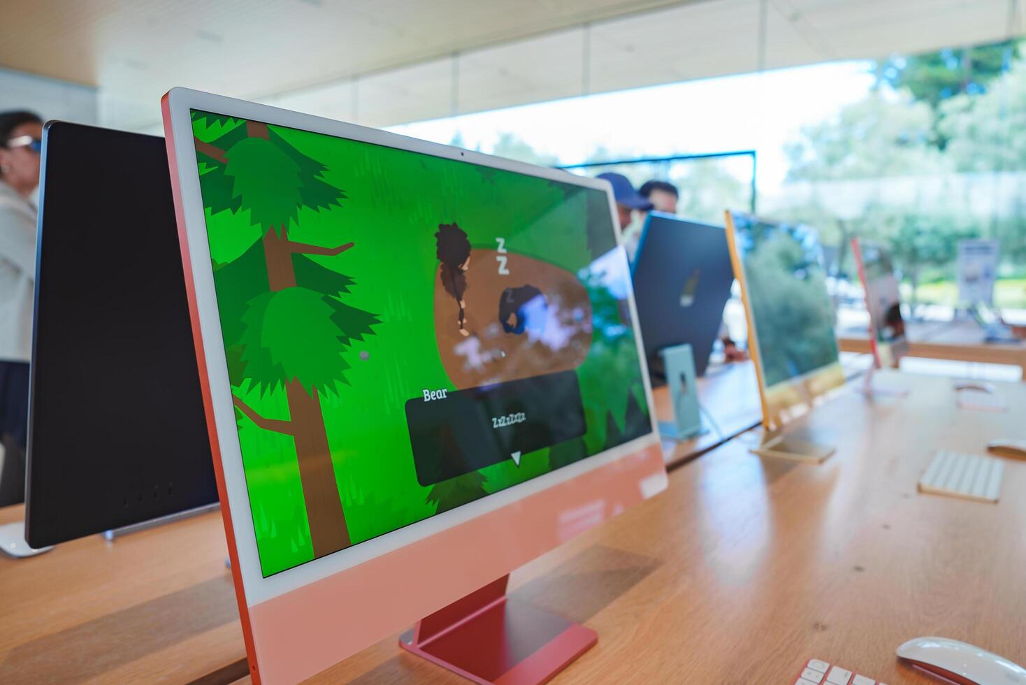 Modern Apple iMacs on display at an Apple Store in Mountain View, California. Colorful graphics on screens, bright and airy environment with customers in background. photo