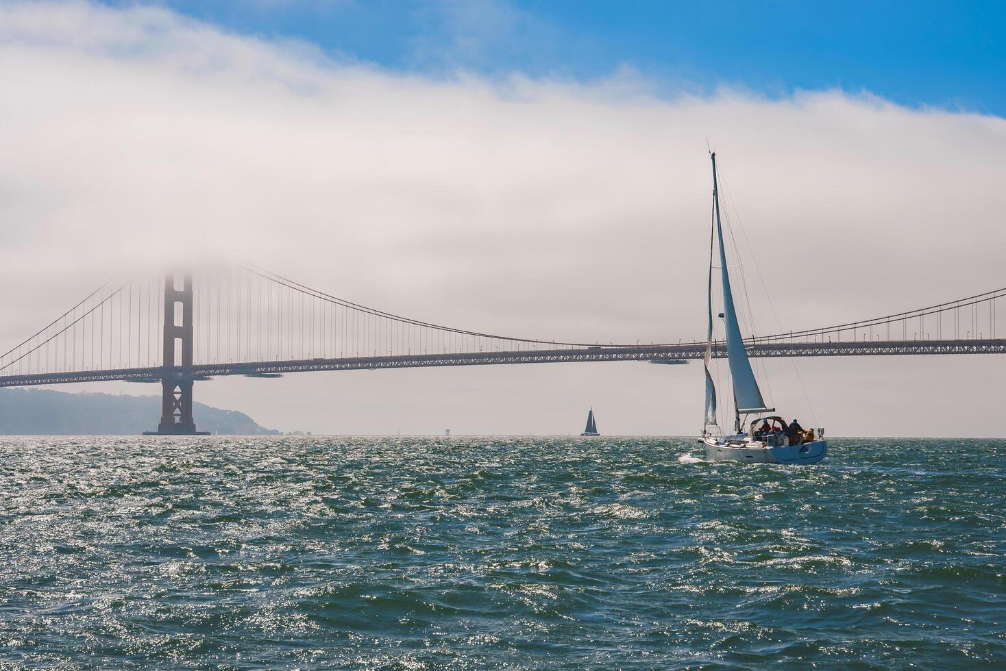 Explore a tranquil nautical scene with the iconic Golden Gate Bridge in San Francisco. Blue waters, sailboats, and a clear sky create a picturesque setting. photo