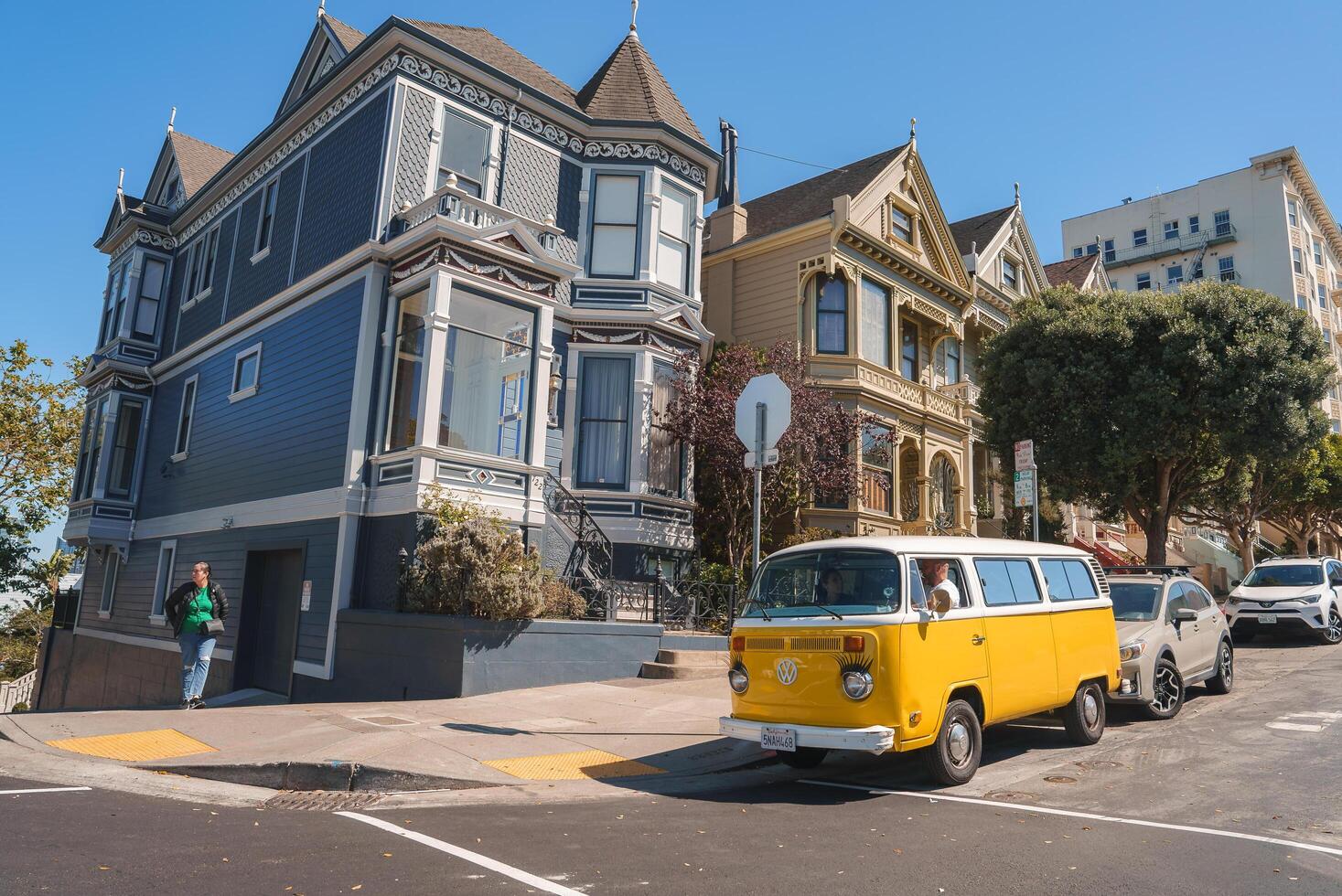Explore the iconic architecture and steep inclines of San Francisco with a picturesque street scene showcasing Victorian houses, a VW Bus, and modern city life. photo