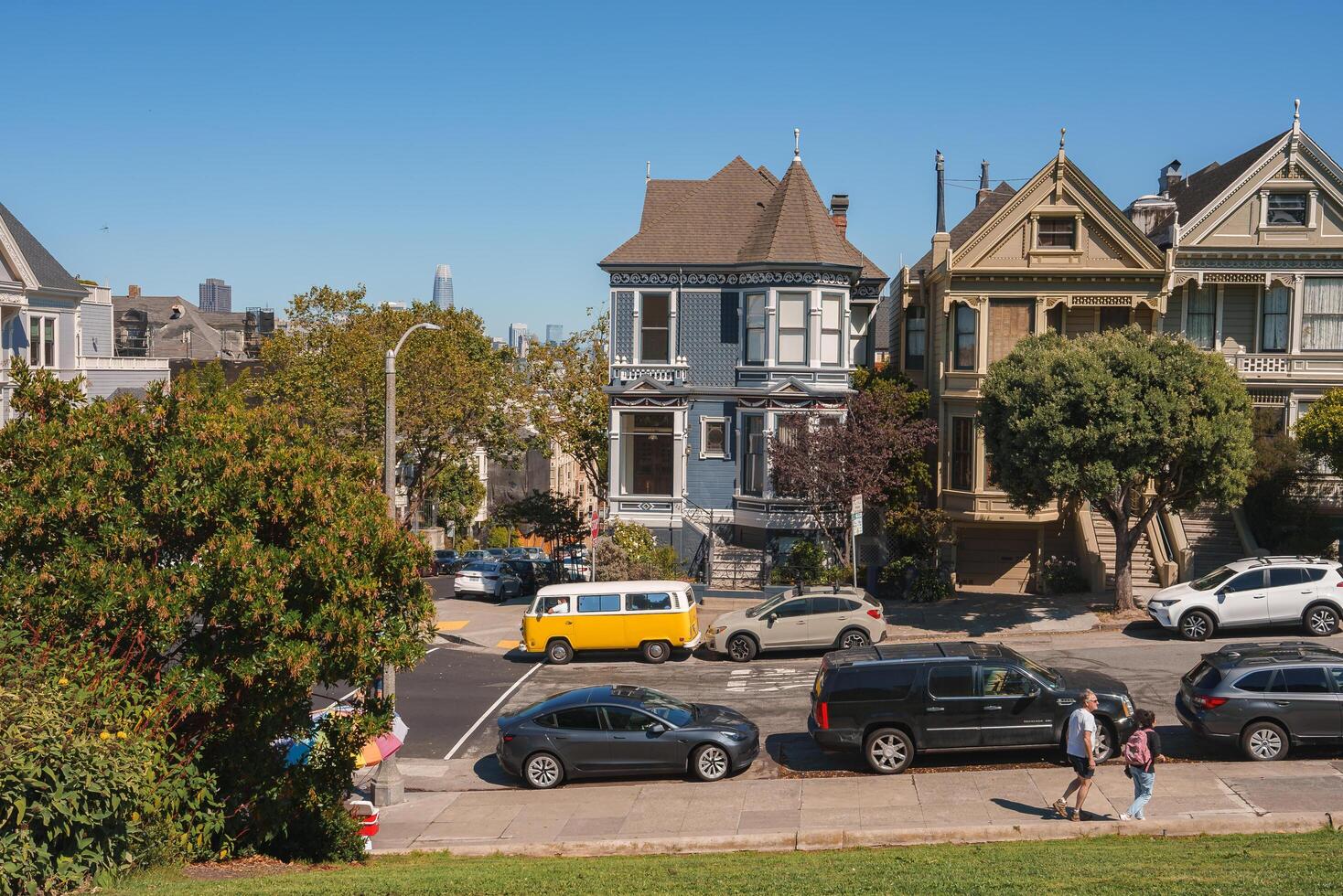 Victorian houses in sunny San Francisco showcase iconic charm with ornate detailing, vibrant colors, and lush greenery. Unique yellow van pops against blue sky in tranquil residential neighborhood. photo