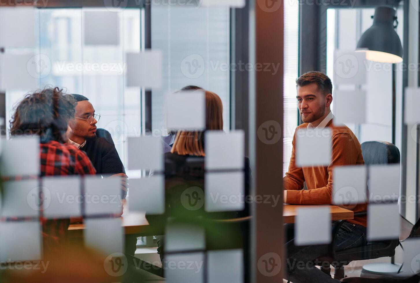 In a sleek glass office space, a team of business professionals engage in lively discussions and exchange strategic ideas, showcasing collaboration and innovation at the heart of modern corporate photo