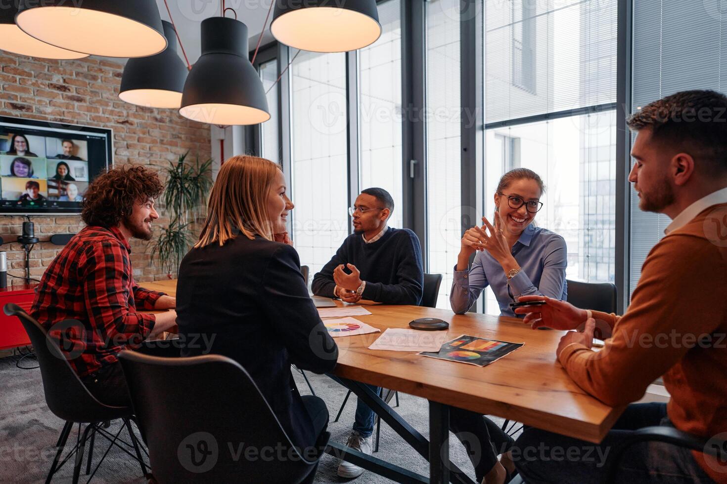 In the vibrant ambiance of a modern startup office, a diverse team of business professionals engage in discussions on various projects and develop new business strategies, epitomizing creativity and photo