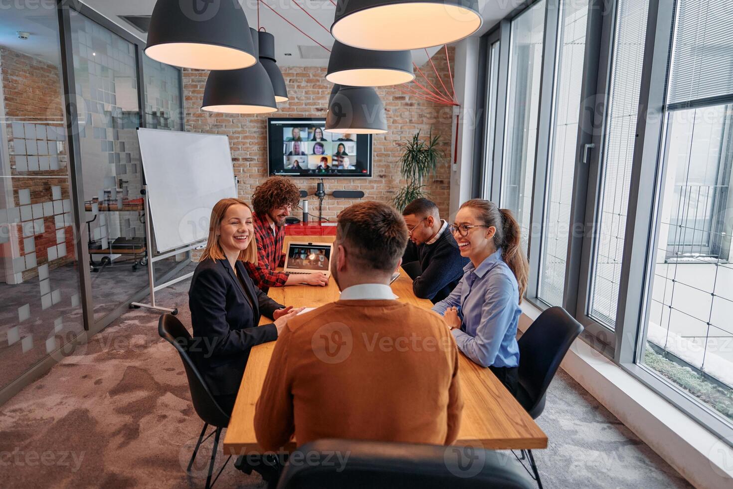 In the vibrant ambiance of a modern startup office, a diverse team of business professionals engage in discussions on various projects and develop new business strategies, epitomizing creativity and photo
