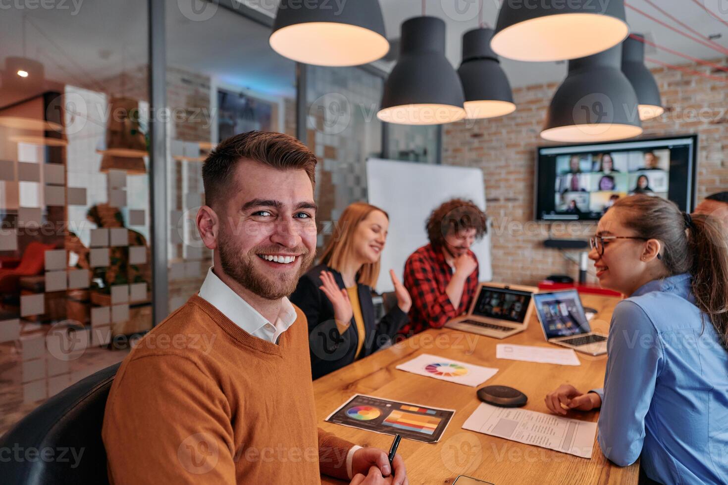 In the vibrant ambiance of a modern startup office, a diverse team of business professionals engage in discussions on various projects and develop new business strategies, epitomizing creativity and photo