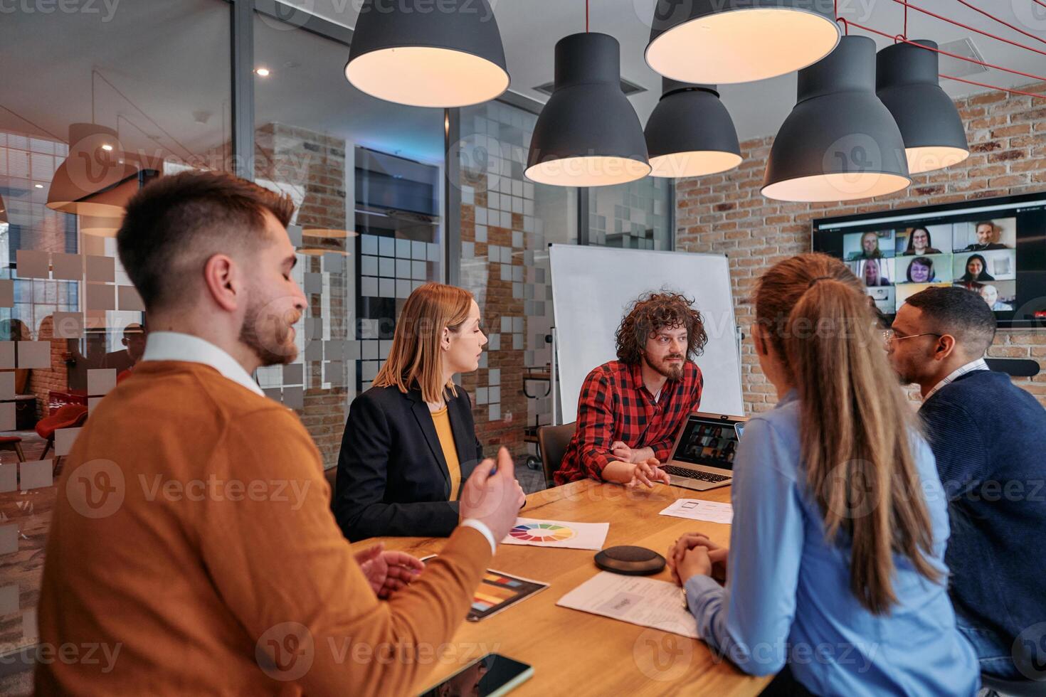 In the vibrant ambiance of a modern startup office, a diverse team of business professionals engage in discussions on various projects and develop new business strategies, epitomizing creativity and photo