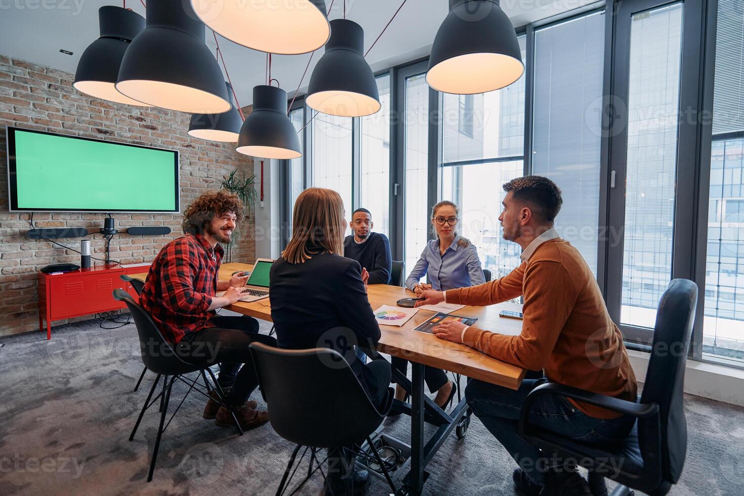 In the vibrant ambiance of a modern startup office, a diverse team of business professionals engage in discussions on various projects and develop new business strategies, epitomizing creativity and photo