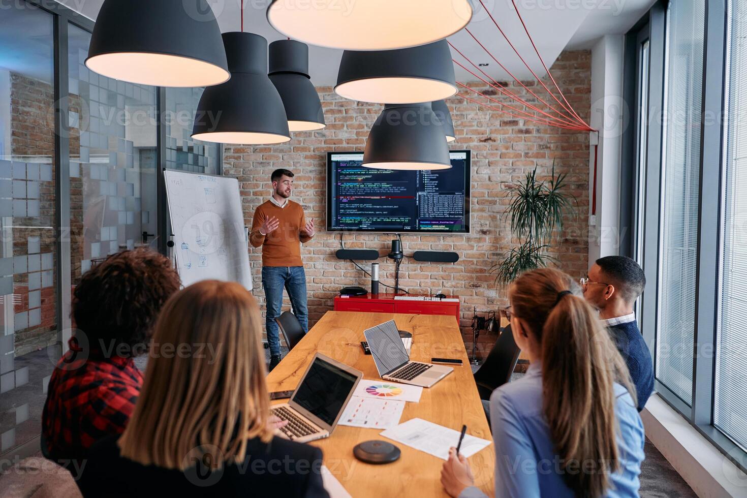 In a corporate setting businessman leads a meeting, passionately presenting a business plan to his attentive team, fostering collaboration and strategic thinking photo
