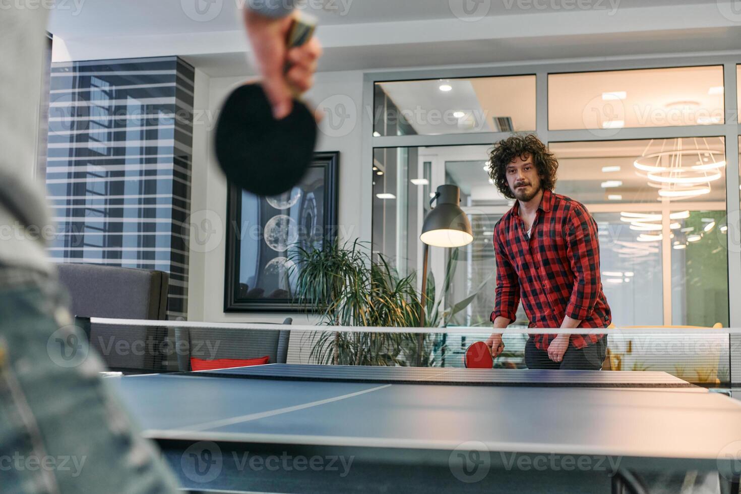 Business colleagues take a break from work to enjoy a game of table tennis, fostering teamwork and camaraderie in the workplace photo