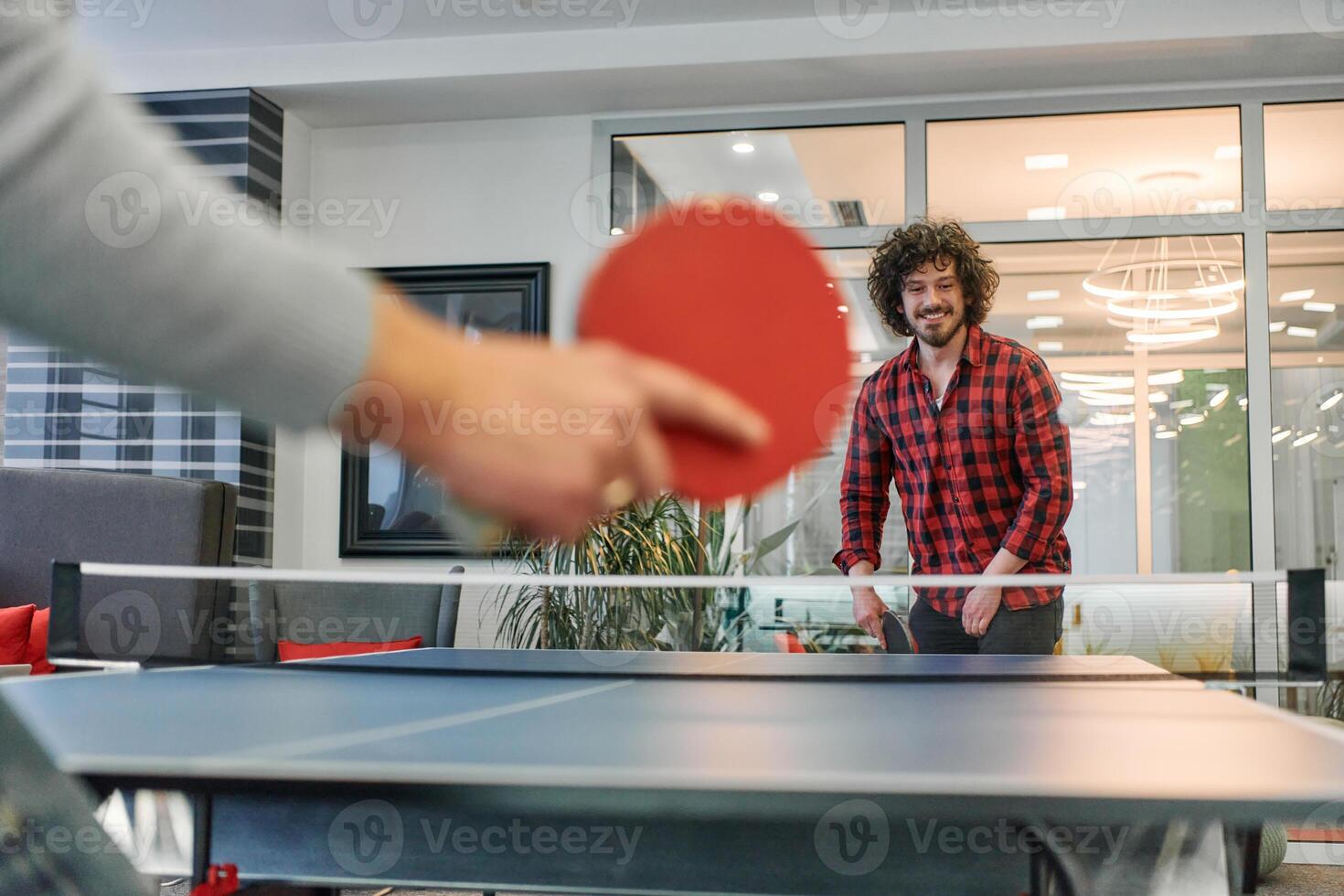 Business colleagues take a break from work to enjoy a game of table tennis, fostering teamwork and camaraderie in the workplace photo
