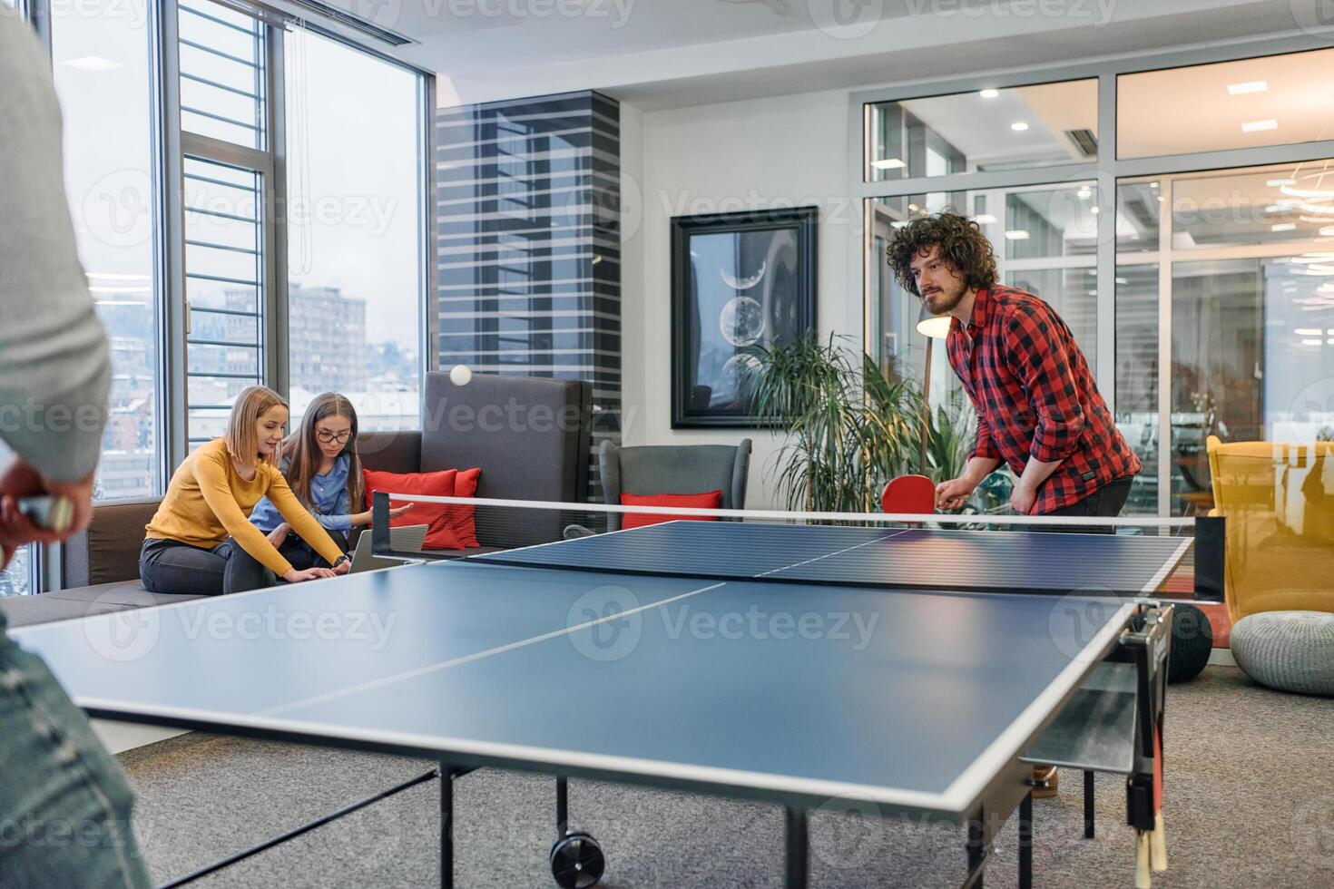 Business colleagues take a break from work to enjoy a game of table tennis, fostering teamwork and camaraderie in the workplace photo