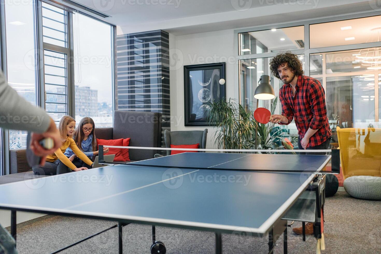 Business colleagues take a break from work to enjoy a game of table tennis, fostering teamwork and camaraderie in the workplace photo