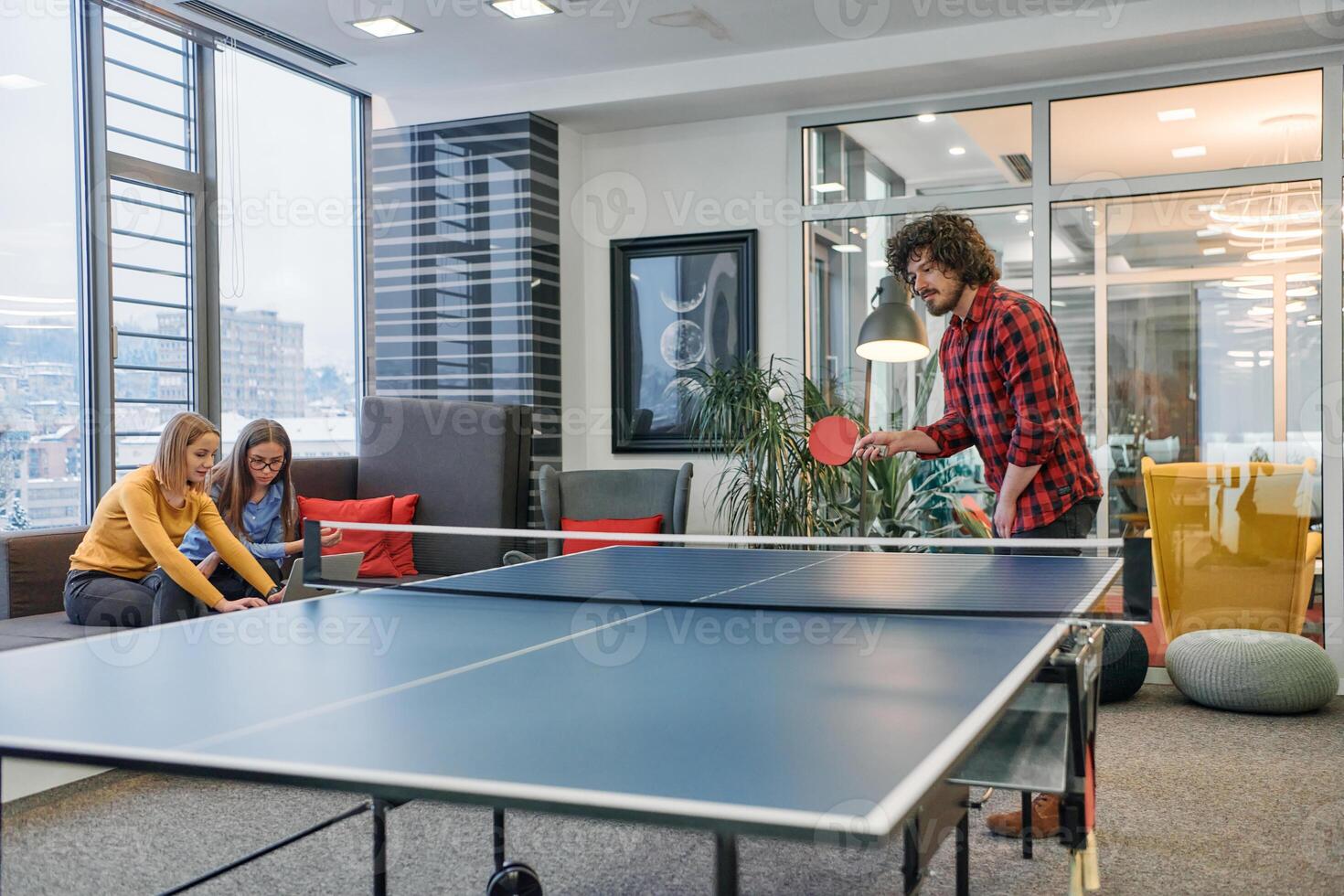 Business colleagues take a break from work to enjoy a game of table tennis, fostering teamwork and camaraderie in the workplace photo