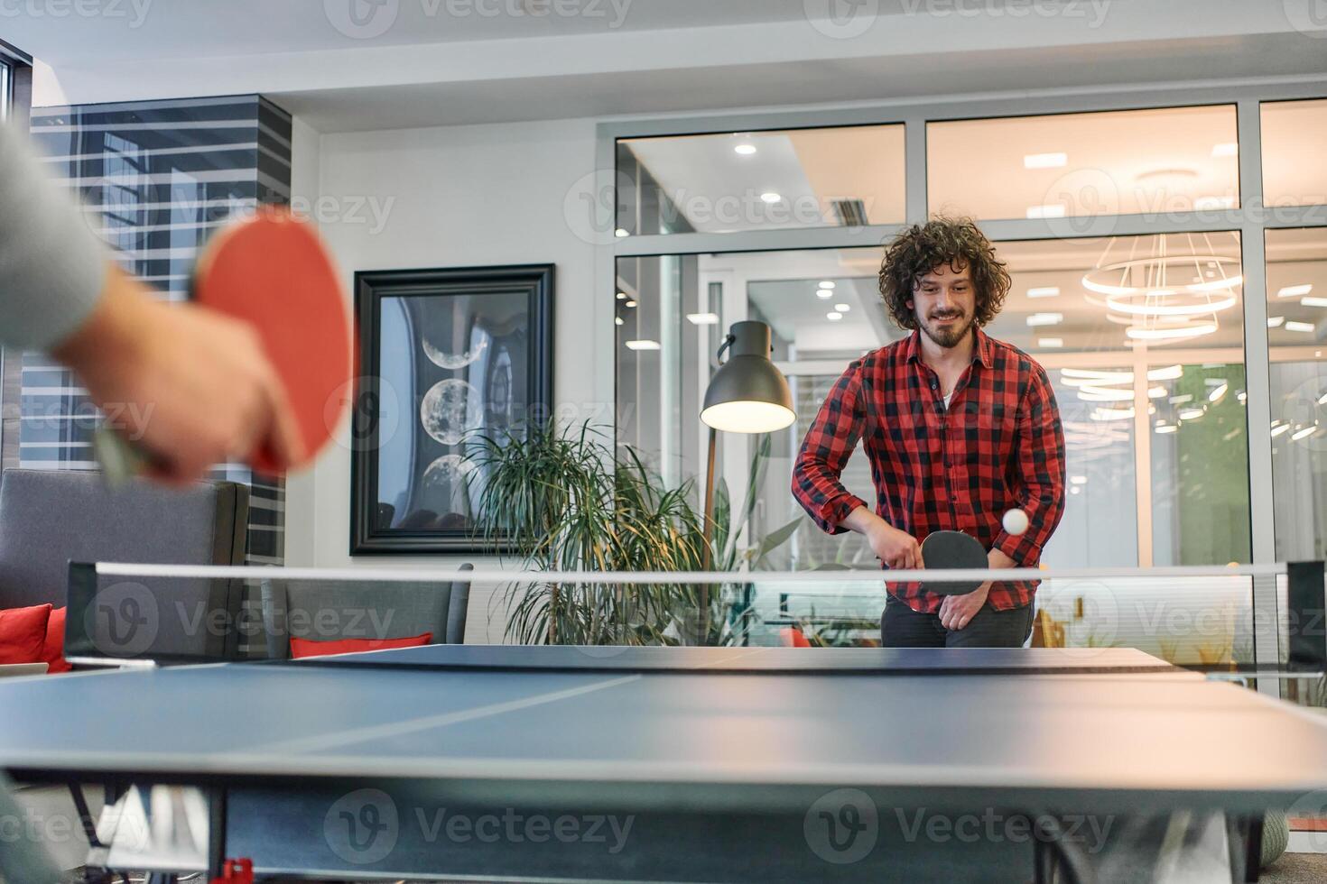 Business colleagues take a break from work to enjoy a game of table tennis, fostering teamwork and camaraderie in the workplace photo
