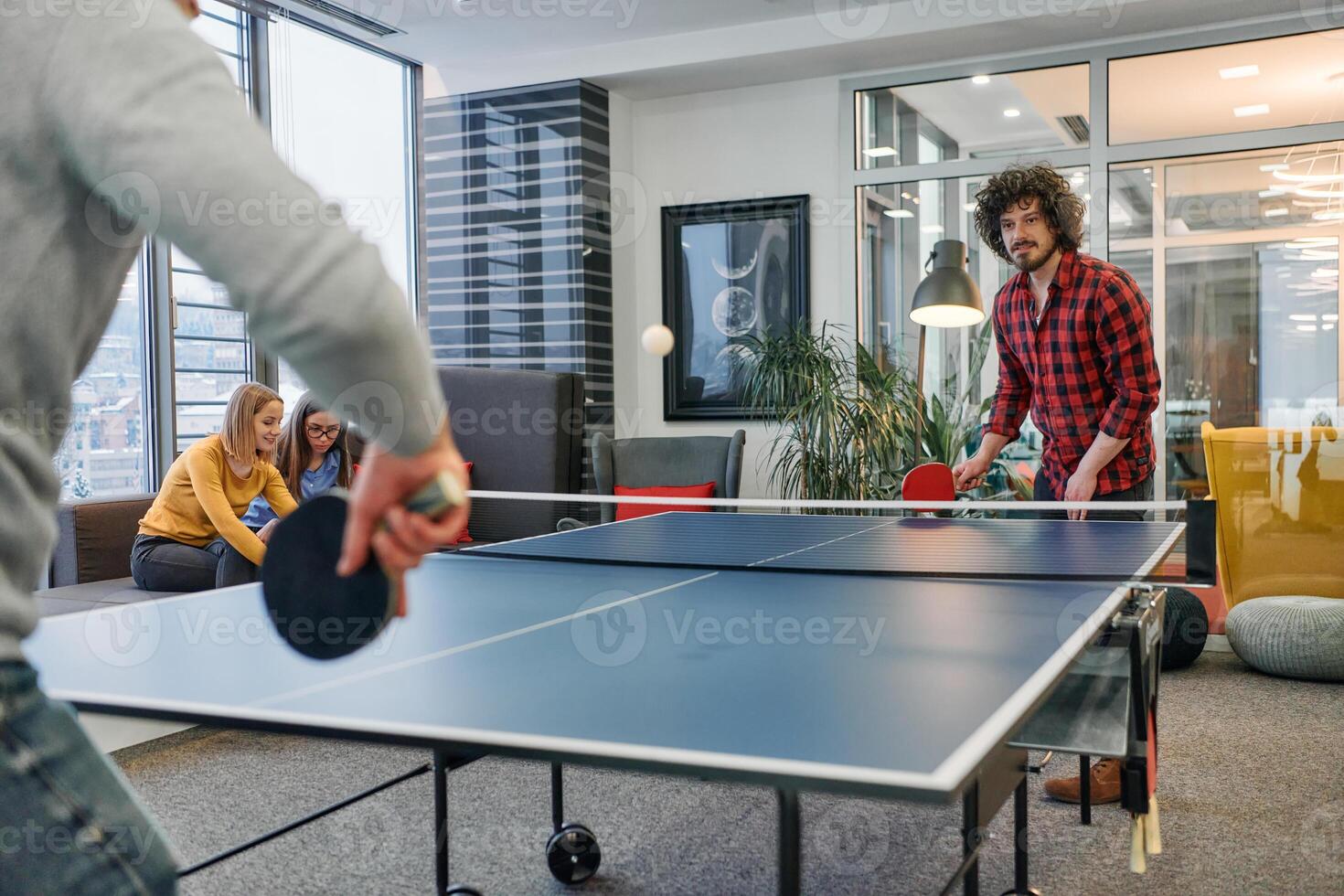 Business colleagues take a break from work to enjoy a game of table tennis, fostering teamwork and camaraderie in the workplace photo