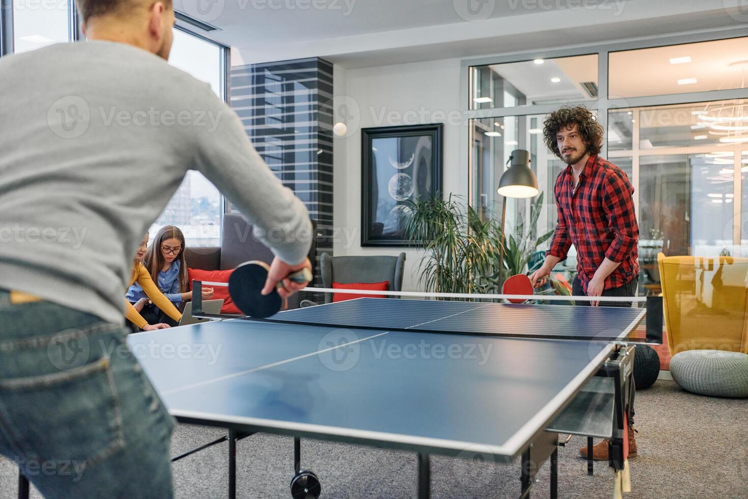 Business colleagues take a break from work to enjoy a game of table tennis, fostering teamwork and camaraderie in the workplace photo