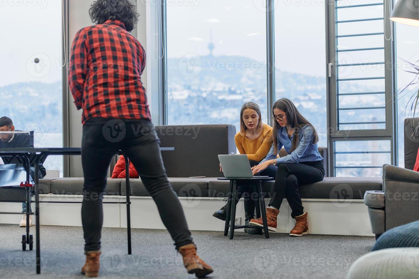 Business colleagues take a break from work to enjoy a game of table tennis, fostering teamwork and camaraderie in the workplace photo