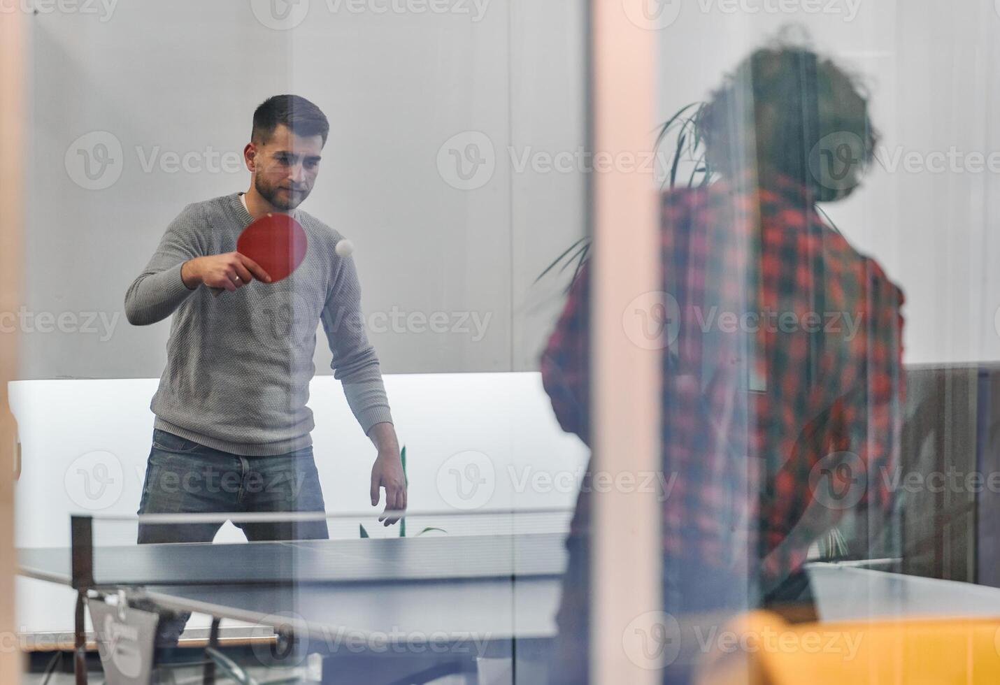 Business colleagues take a break from work to enjoy a game of table tennis, fostering teamwork and camaraderie in the workplace photo
