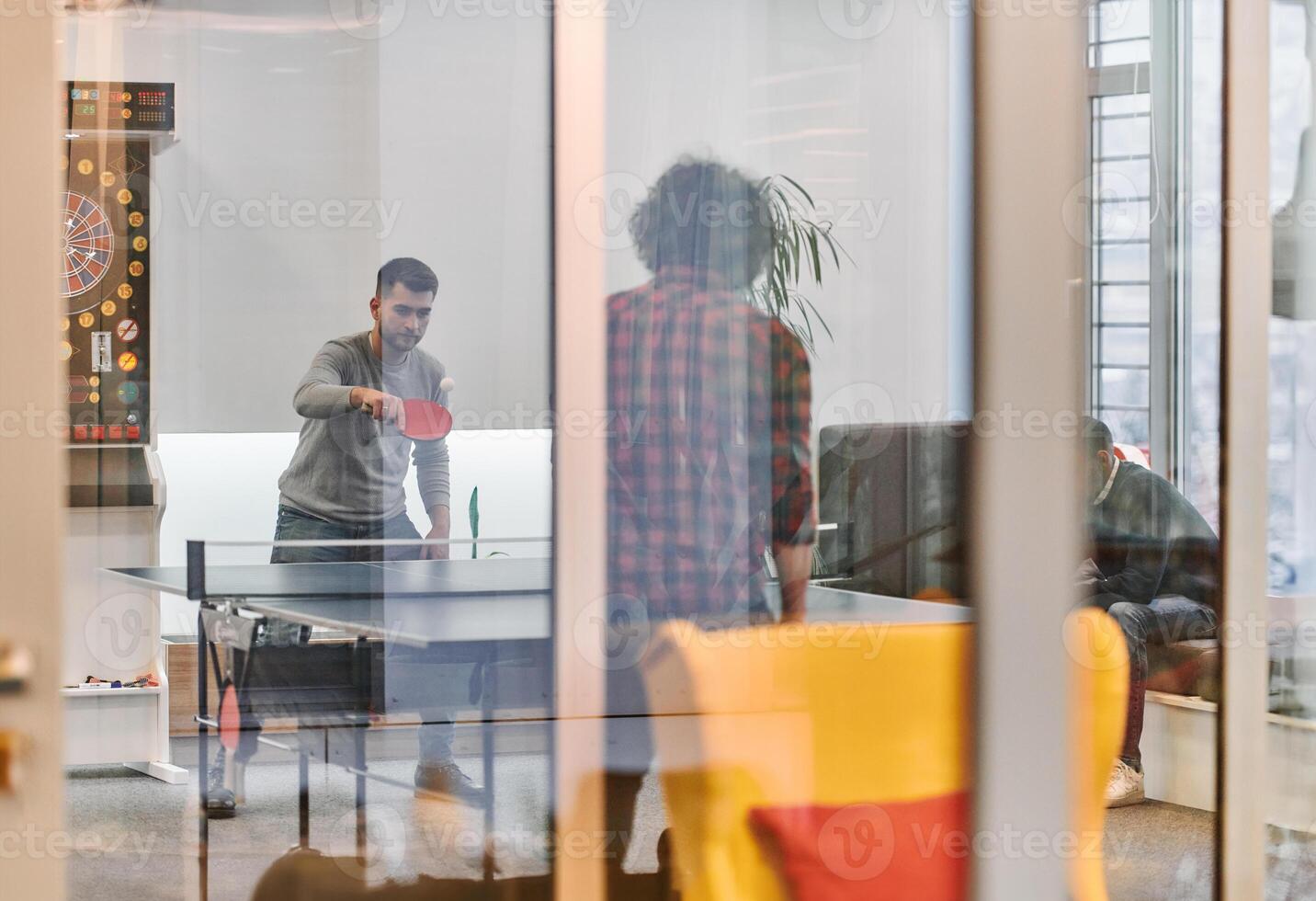 Business colleagues take a break from work to enjoy a game of table tennis, fostering teamwork and camaraderie in the workplace photo