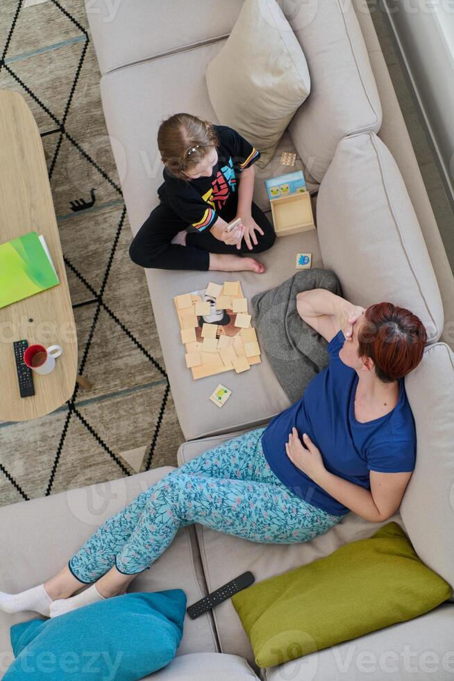 Top View of Mother and Daughter Enjoying a Fun Board Game on the Couch at Home photo