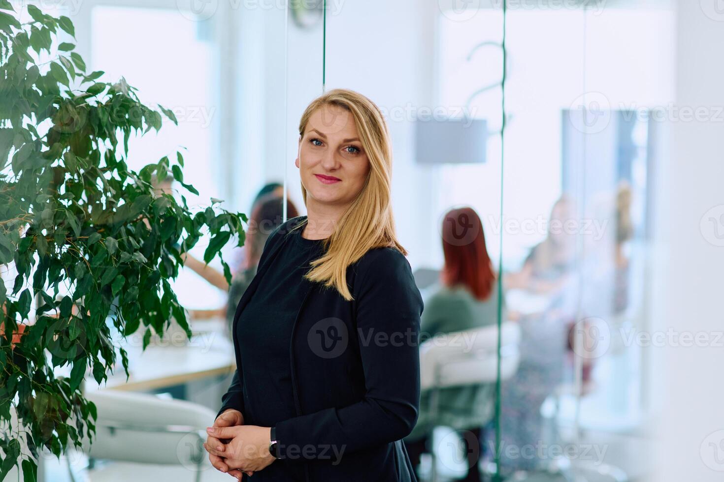 Portrait of a Blonde Businesswoman in a Modern Office with Her Workspace and Colleagues in the Background. photo