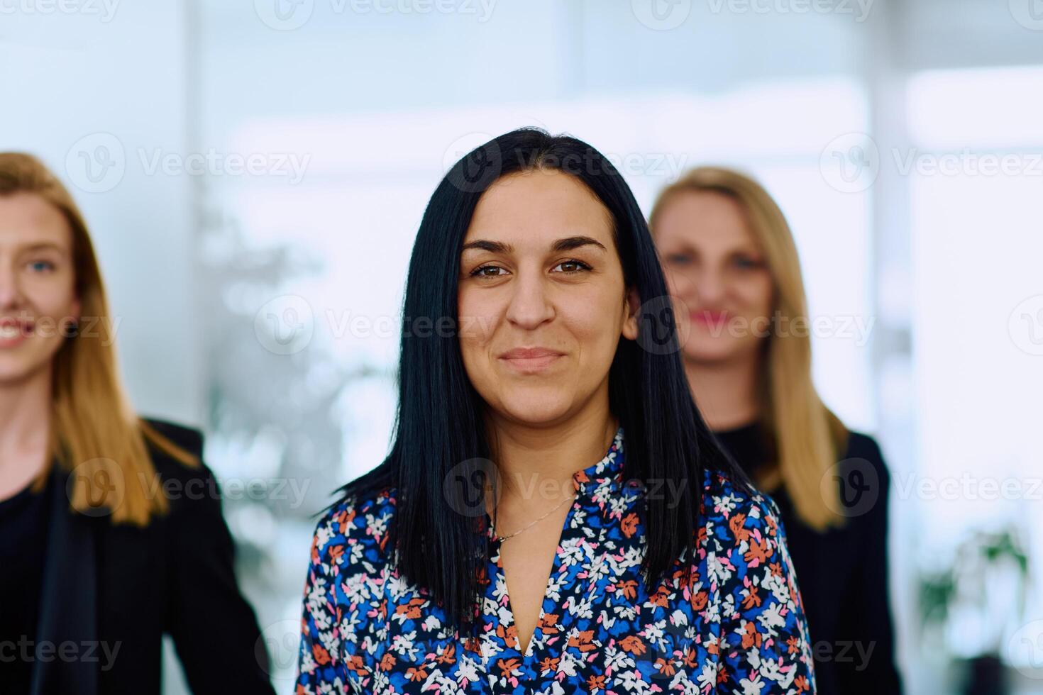 Confident businesswomen stride through the office hallway, deep in discussion. photo