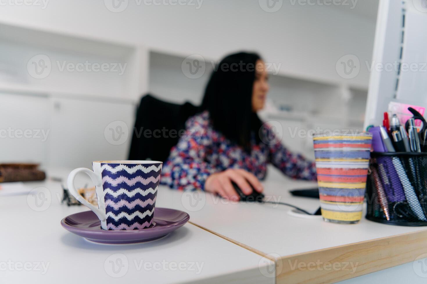 Businesswoman Working on Computer with Coffee Mug in Foreground photo