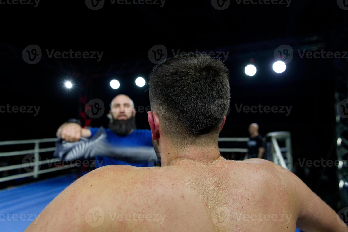 Cornered boxer receives strategic advice from trainer during intense bout. photo
