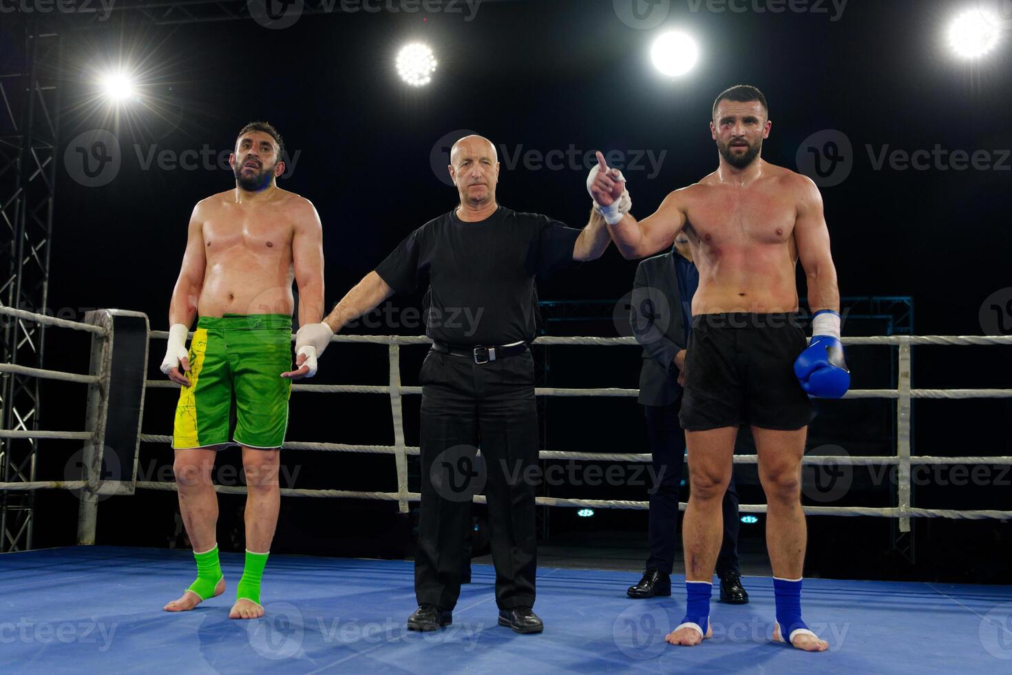 Boxing referee declares victorious fighter amidst the aftermath of an intense bout. photo