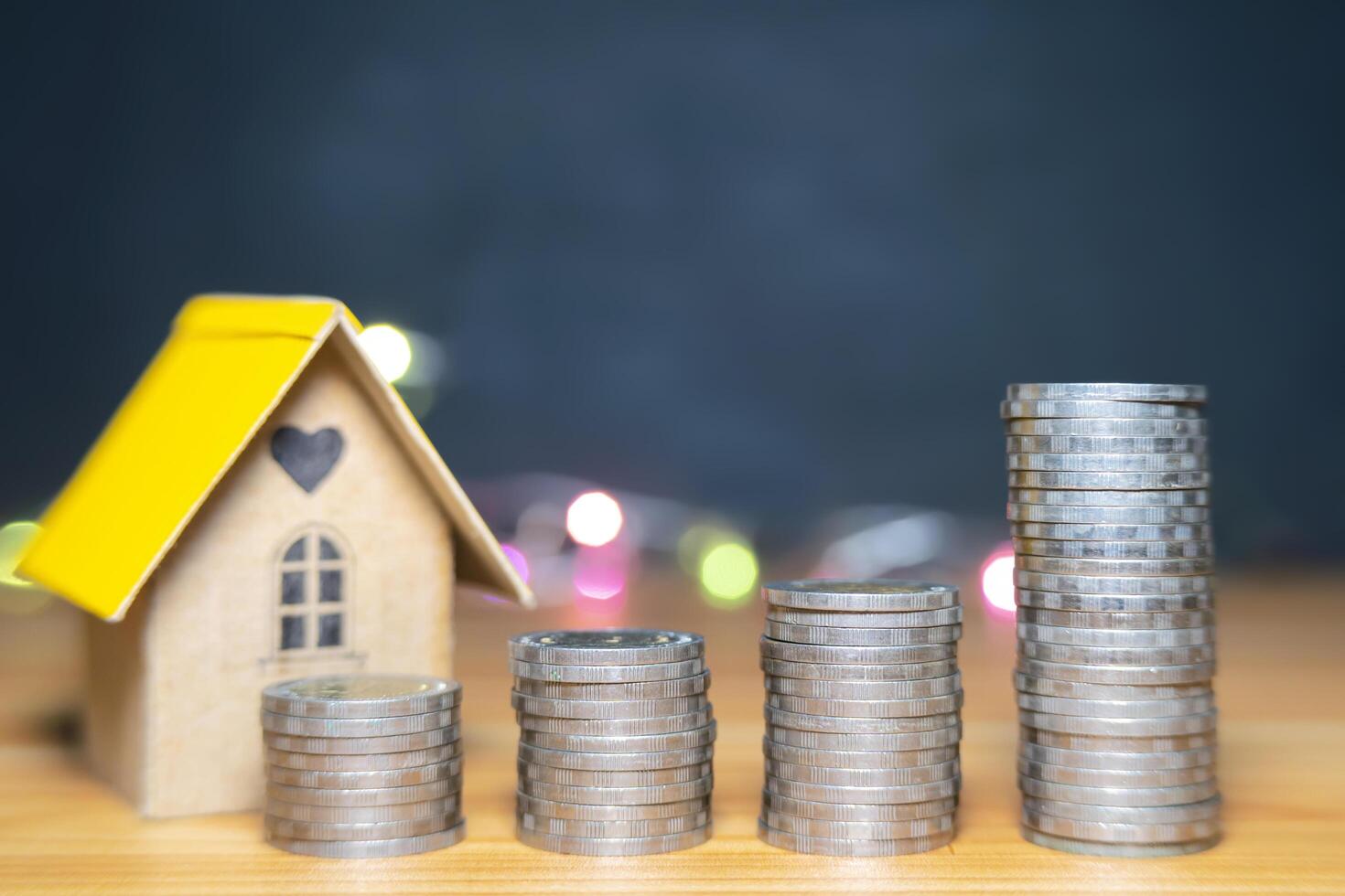 House model and stack of coins for Investing in Mortgage Funds, Finance, and Growing Interest Rate Home Loans. photo