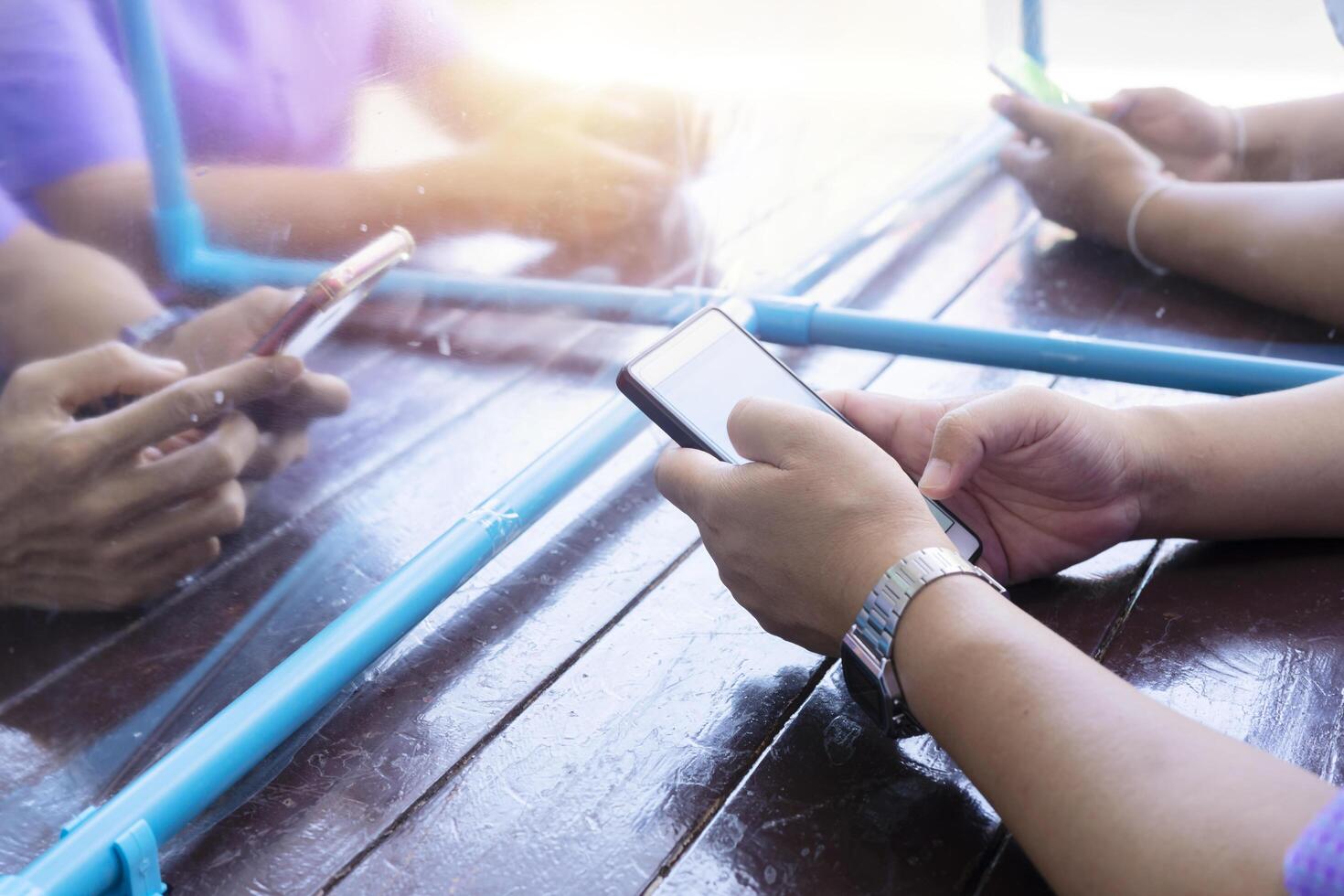 A group of people who are using a smartphone with a partition between them. Concept of staying physically apart for infection control intended to stop or slow down the spread of COVID-19 conoravirus photo