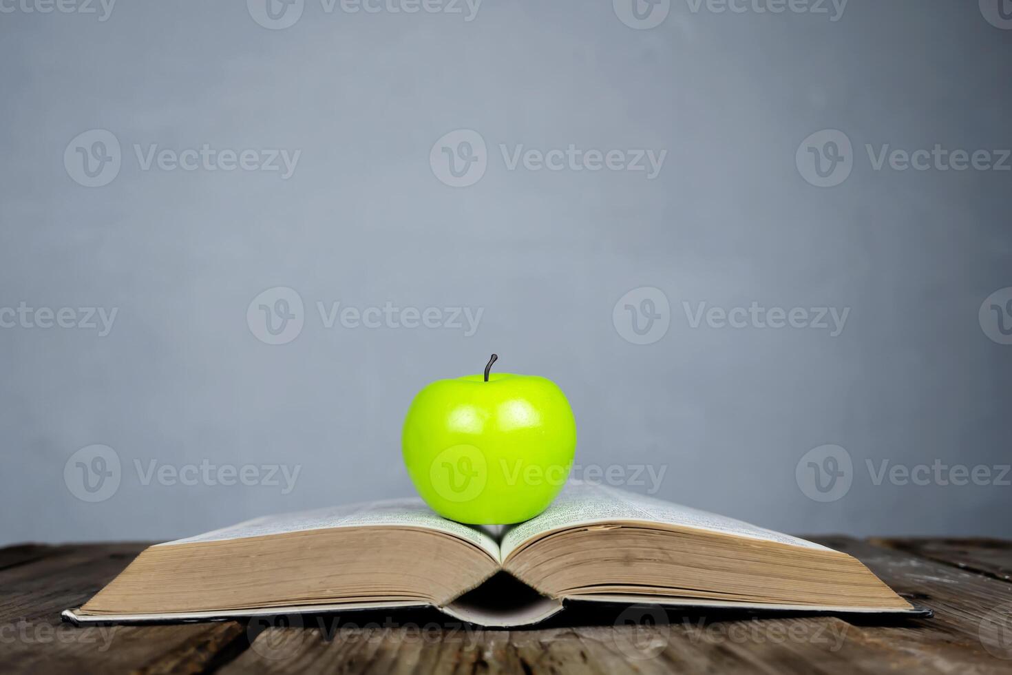 Books placed on the table and on top are green apple. photo