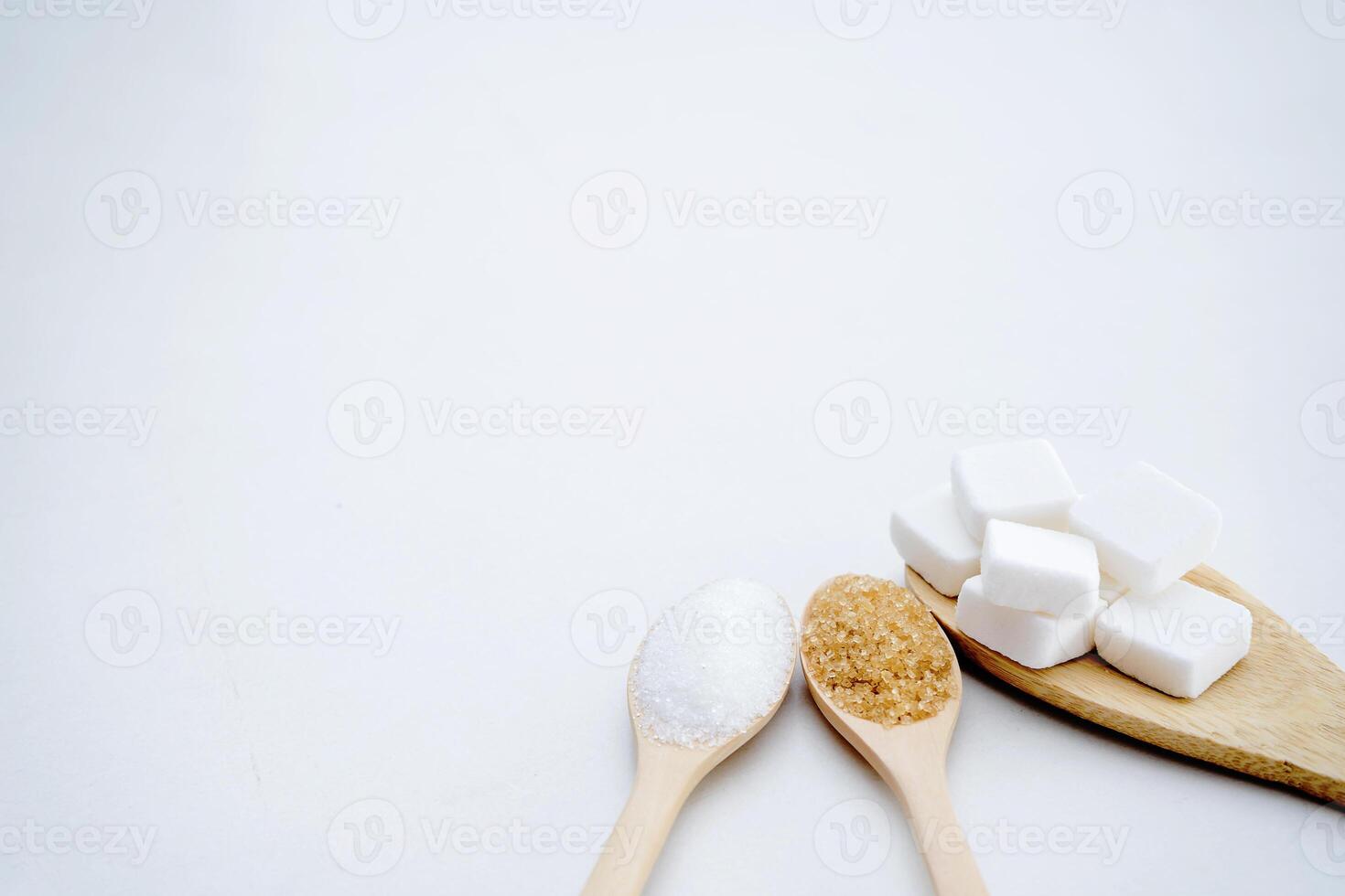 White sugar, brown sugar, sugar cubes, placed in a wooden spoon. photo