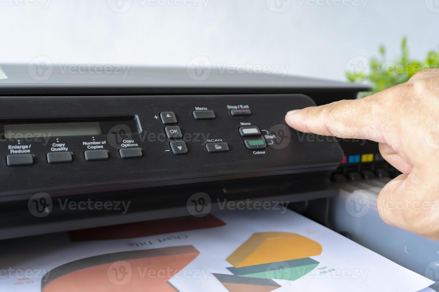 Fingers that are pressing the button, The printer is fully functional,Located on the desk. photo