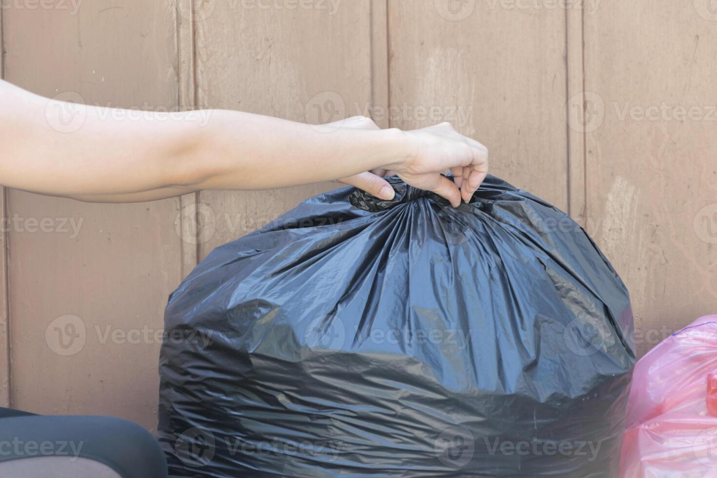 woman putting garbage bag into trash can. Bind it to make it easy to move. photo