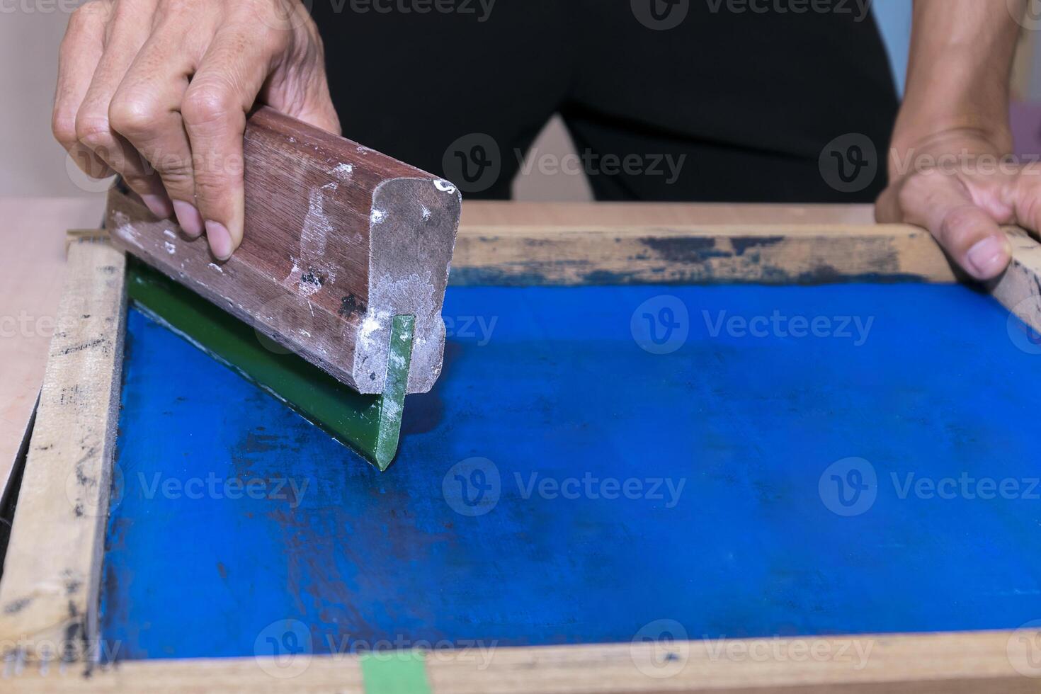 Young confident, experienced male working with squeegee on a small factory. photo