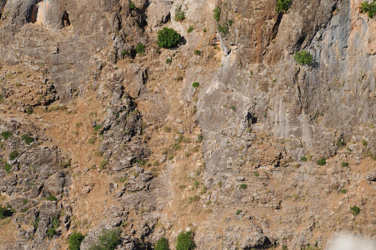 Natural rock formation with small patches of greenery in a rugged mountainous area photo