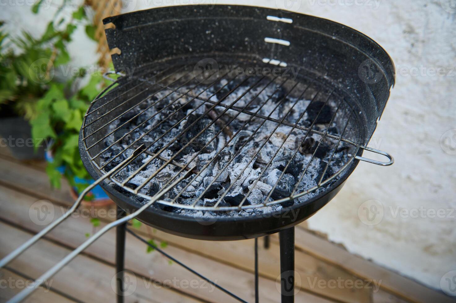 Empty charcoal grill with ashes and charred remains after a barbecue in a backyard setting photo