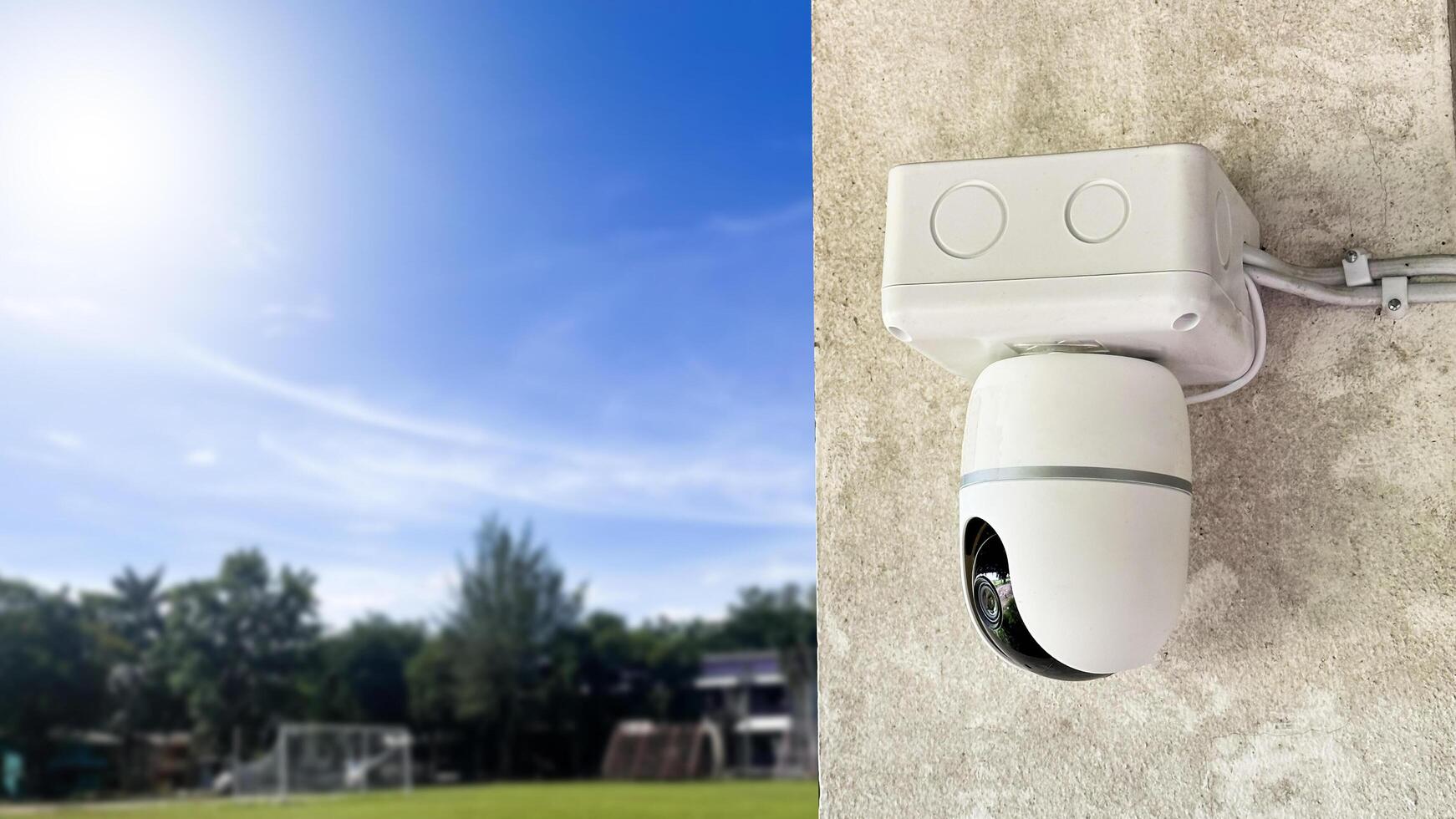 A CCTV camera is set against a blurred background with a vibrant blue sky. photo