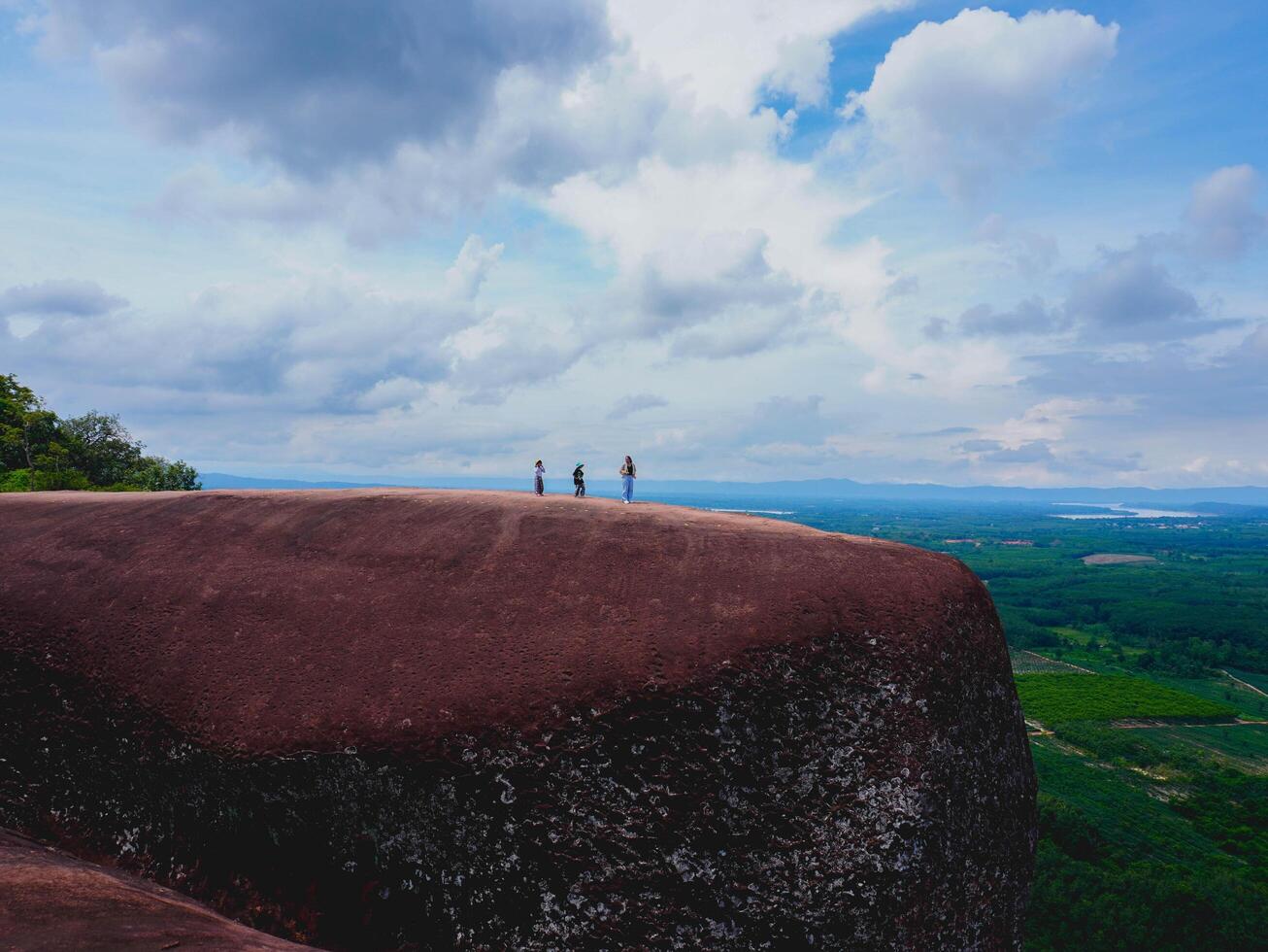 Adventurers stand on a large boulder in the middle of a forest in a national park, Three Whale Rock or Hin Sam Whales in Buegkan province, Thailand. photo