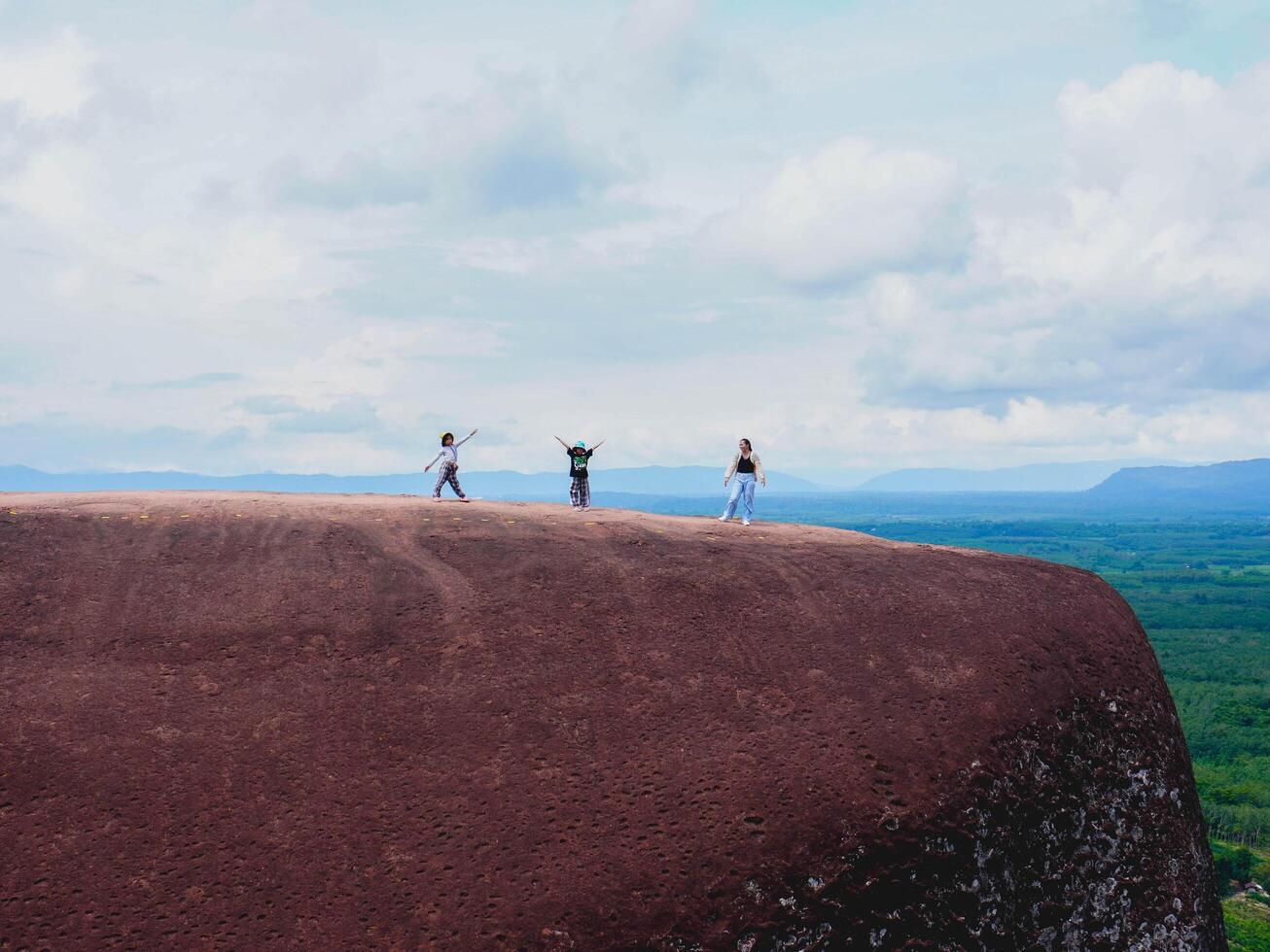 Adventurers stand on a large boulder in the middle of a forest in a national park, Three Whale Rock or Hin Sam Whales in Buegkan province, Thailand. photo