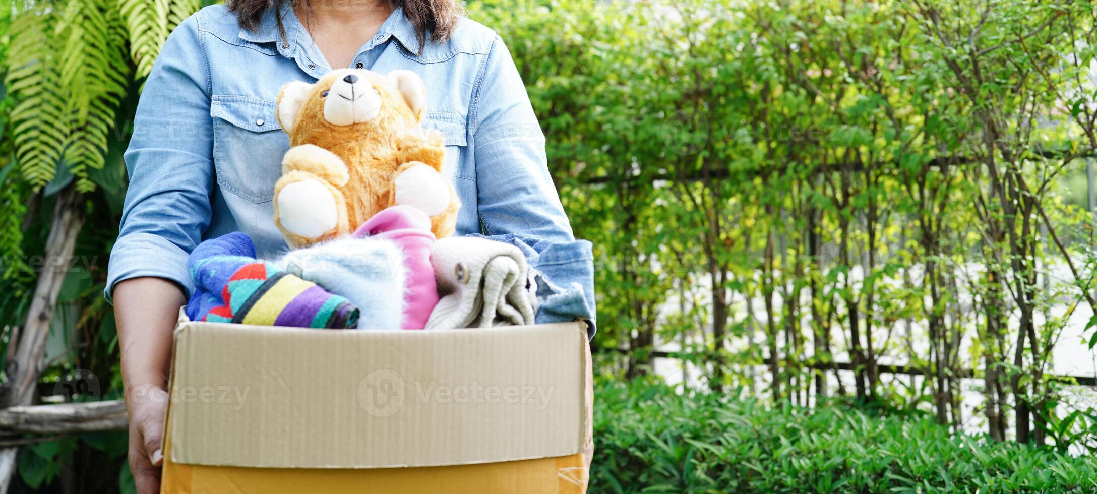 Volunteer collect cloth and doll in cardboard box to donate. photo
