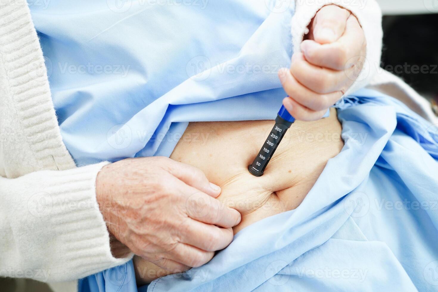 Asian senior woman making injection insulin pen in belly to treatment diabetes. photo